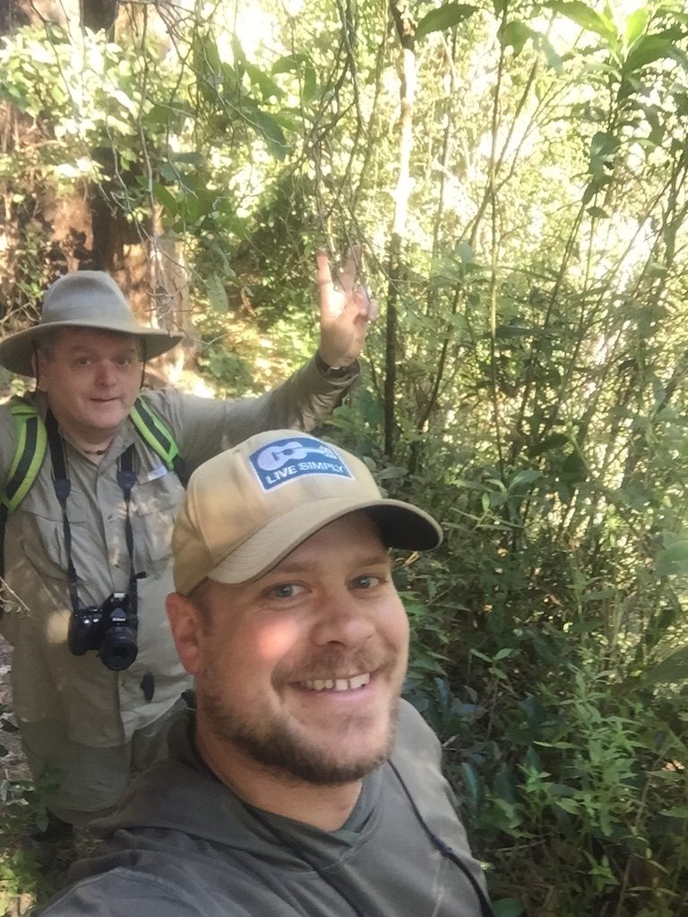 Selfie of two researchers in hats on a forest trail