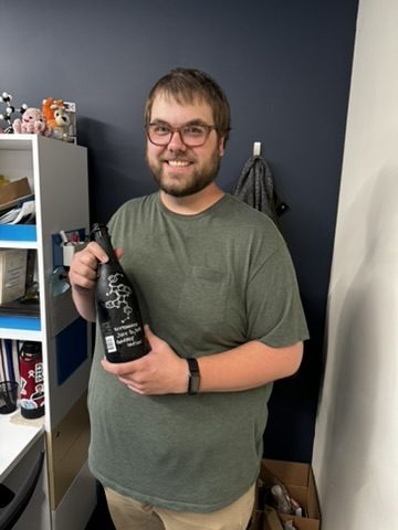 Student holding a champagne bottle with a structure drawn on it