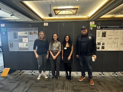 Four people standing in front of research posters